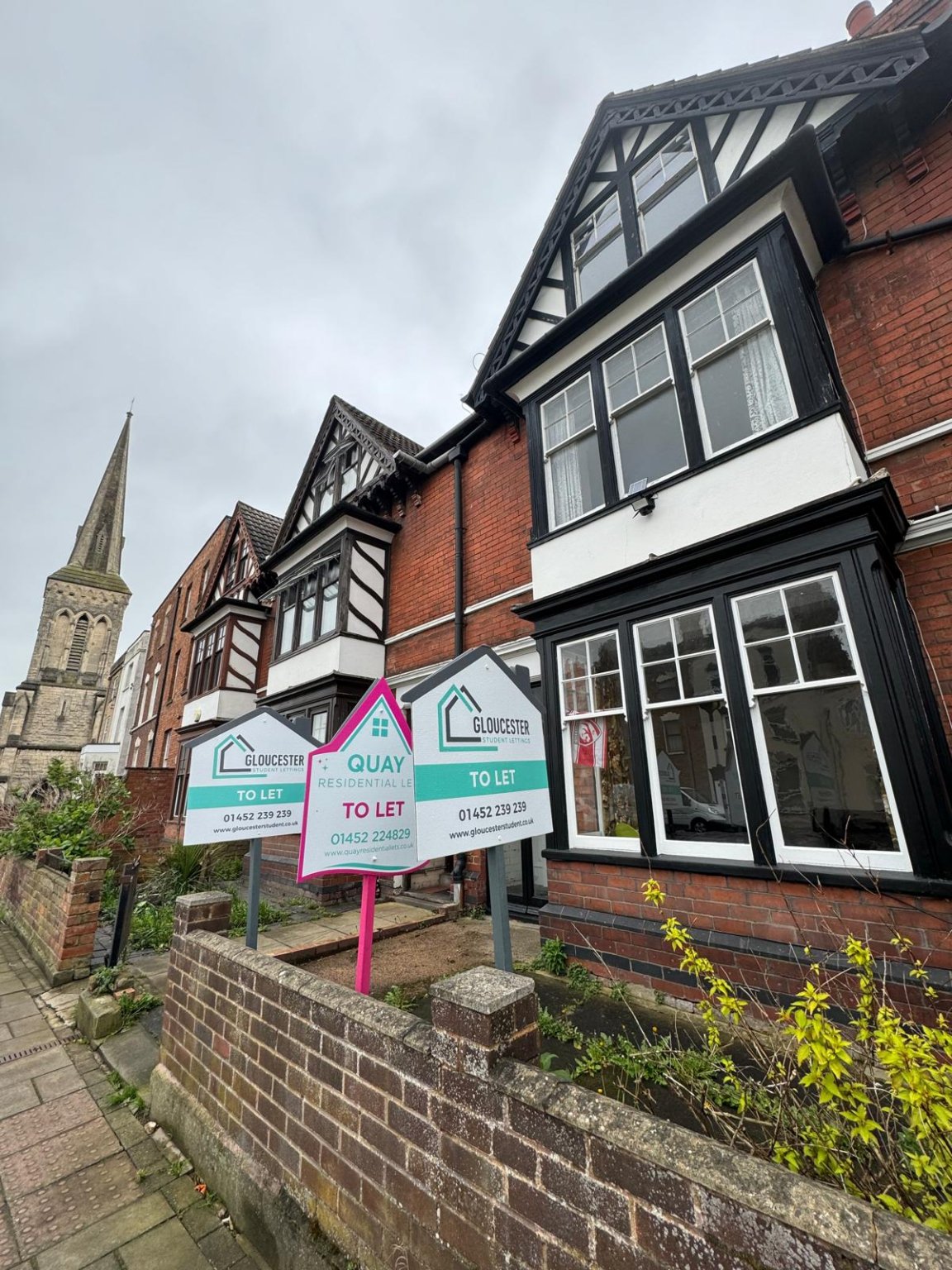 Image of a house with both gloucester student letting and quay residential letting boards outside.