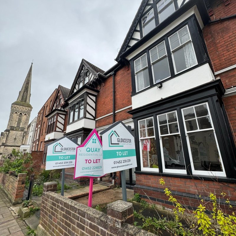 Image of a house with both gloucester student letting and quay residential letting boards outside.